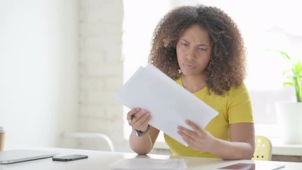 African Woman Upset while Reading Documents in Office