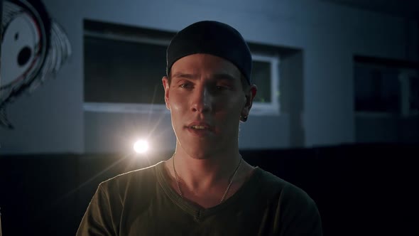 Portrait Shot of Handsome Caucasian Young Man Turning Face to Camera and Looking Shrewd in Dark Hall