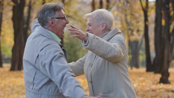 Joyful Elderly Woman and Man in Autumn Park Grandpa Holding Phone Aged Couple Receive Good News