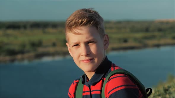 Close Up Portrait Caucasian Boy Teenager in a Red Shirt with a Backpack on His Back, at Sunset