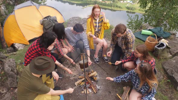 Young Tourists Having a Rest Roasting Mushrooms on Sticks