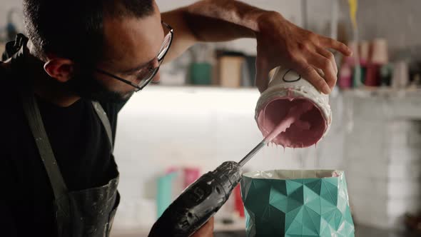 Male sculptor handyman creates a handmade vase. The paint is poured into the object.