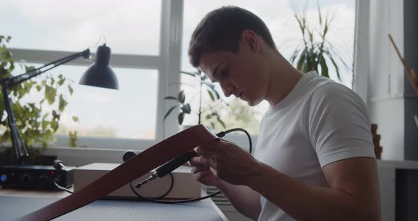 Young Leather Worker Examining Leather Belt During Manufacturing Process