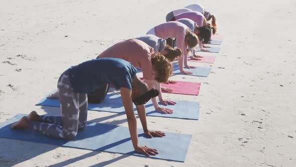 Multi-ethnic group of women doing yoga position on the beach and blue sky background