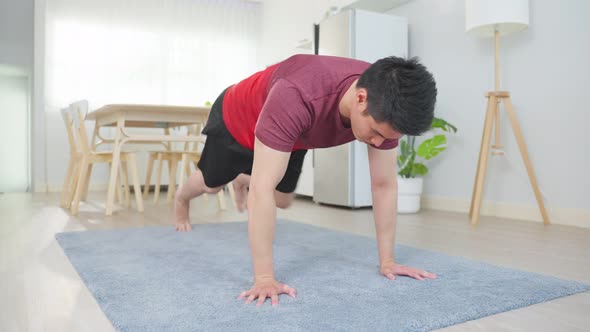 Asian handsome active young man doing exercise on floor in living room.