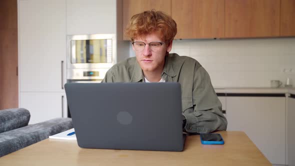 Focused Young Ginger Irish Man Watching Webinar Video Course Writing Notes