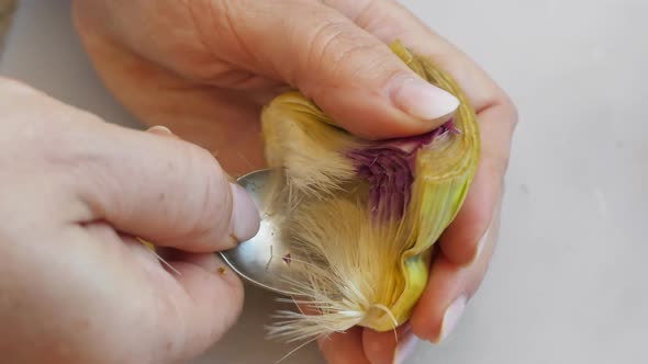 Woman Cleaning Heart of Artichokes with Spoon