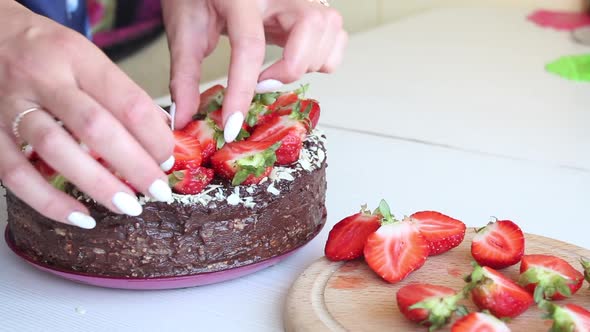 A Woman Decorates A Cake With Strawberries.
