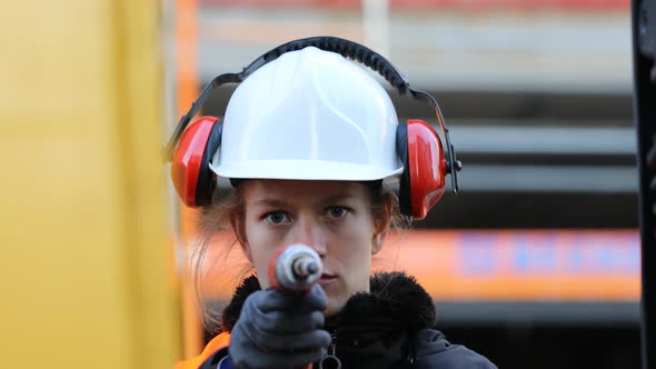 Smiling female technician holding drill and looking at camera