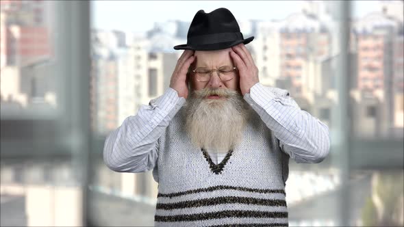 Portrait of a Senior Man Suffering From Sudden Headache and Takingoff Hat