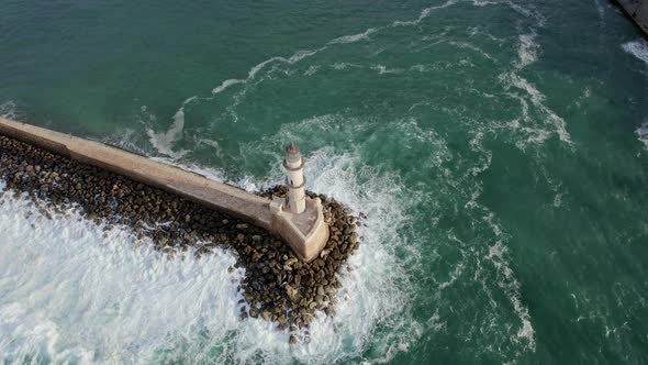 Epic Aerial Drone footage of lighthouse. Cinematic shot. Waves breaking on rocks.