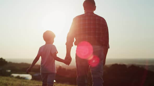 Rear view video of grandfather and grandson walking at sunset. Shot with RED helium camera in 8K.