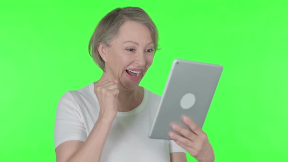 Old Woman Celebrating Success on Tablet on Green Background