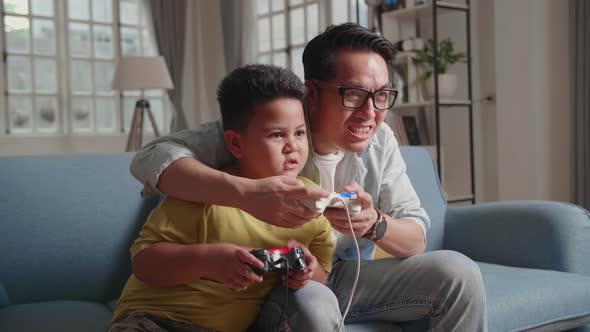 Father And Son Are Sitting On A Couch While Playing A Game, Lost The Game