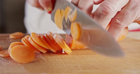 Slow motion close up of a chef knife slicing a carrot