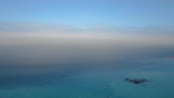 Aerial shot of the calm ocean turning into the blue sky in Malibu, California, USA
