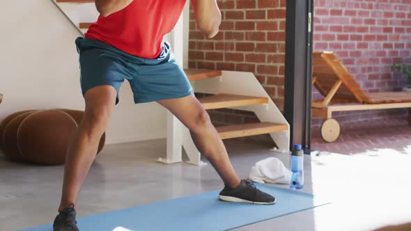 Fit african american man exercising at home and doing stretching at home