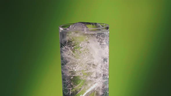 Soda water or a Sprite spinning glass, slow motion bubbles, ice cold.