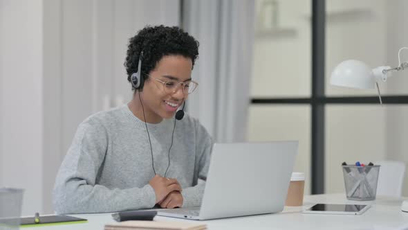African Woman Using Headset for Video Chat on Laptop