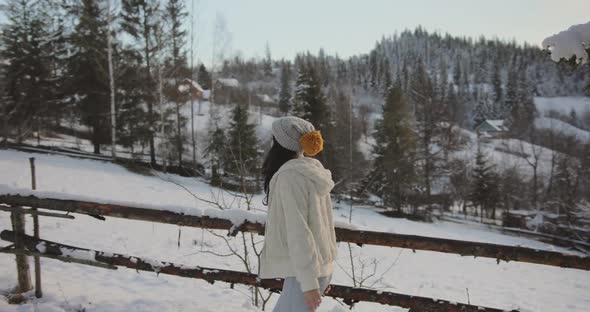 Woman in Winter Clothes Outdoors Against Snowy Mountains and Village