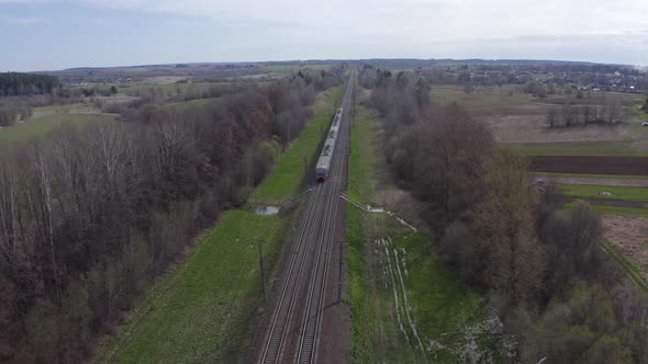 Electric Passenger Train Rides on Rails Among the Fields on a Sunny Spring Day