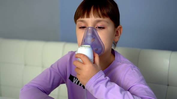 Little Girl Makes Inhalation with Medical Nebulizer While Sitting at Table