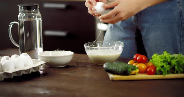 Young Woman Breaks Eggs Injuring the Shell in a Bowl