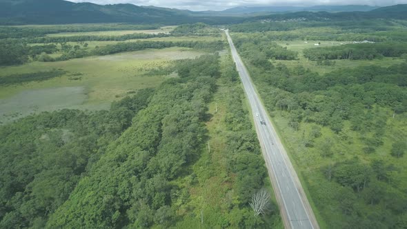 Aerial View Above Cars Driving Along Empty Countryside Road on Sunny Day