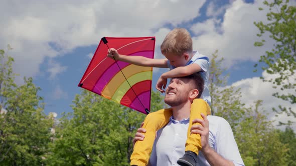 Happy Father and Little Son Playing with Kite on Sunny Day