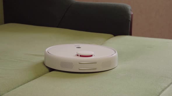 Robot vacuum cleaner vacuuming the bed in the bedroom. Smart home with automated devices