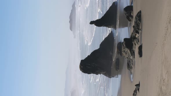 A tourist admires the rock formations of the Oregon coast walking in their reflections.