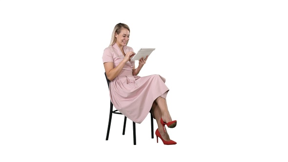 Funny pretty young woman in pink dress sitting on a chair