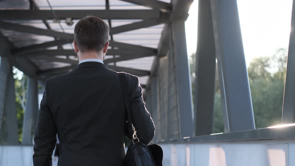 An Office Worker in a Business Suit Walks Right in the Soft Sunlight