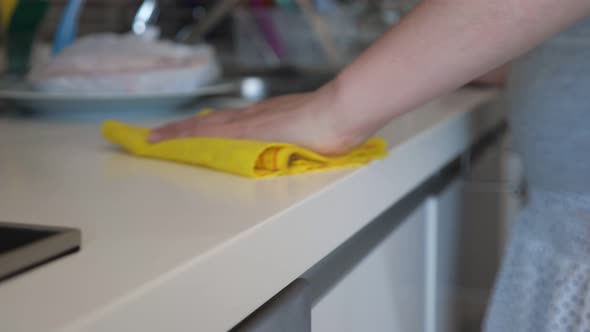 Woman Wipes Kitchen Table Using Yellow Rag Hand Closeup