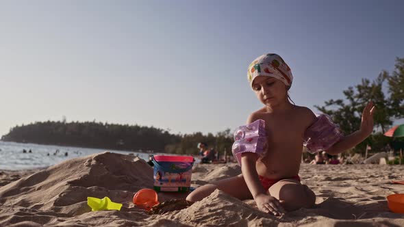 Beautiful Little Girl Playing in Sand On Tropical Beach