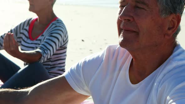 Senior couple doing yoga at beach