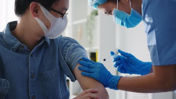 Young lady nurse giving Covid-19 or flu antivirus vaccine to patient wear mask at hospital