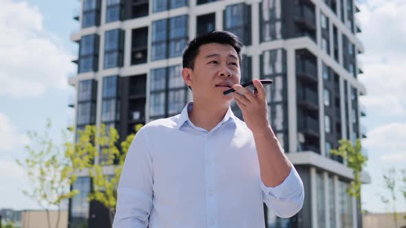 Millennial Chinese Businessman Guy Activating Virtual Assistant on Mobile Phone