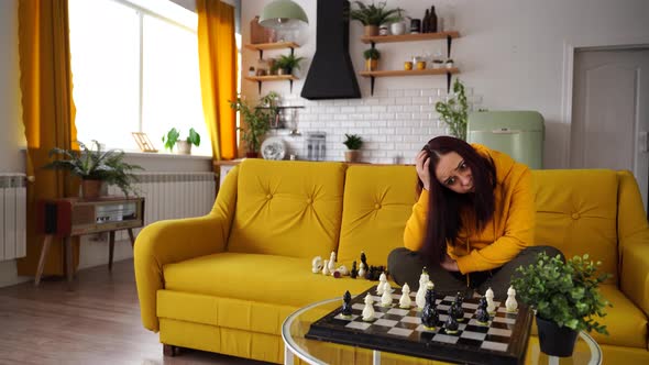 Young Upset Woman Playing Chess Sitting on Sofa