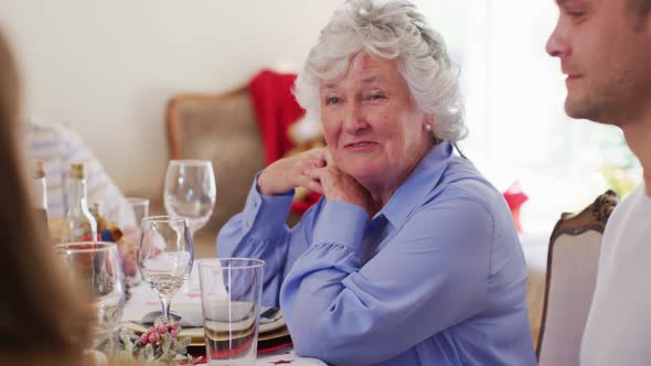 Caucasian senior woman talking while sitting on dining table