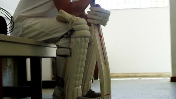 Cricket player sitting on bench in dressing room