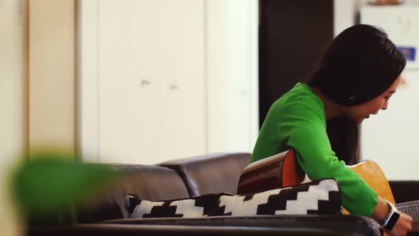 Woman playing guitar in living room