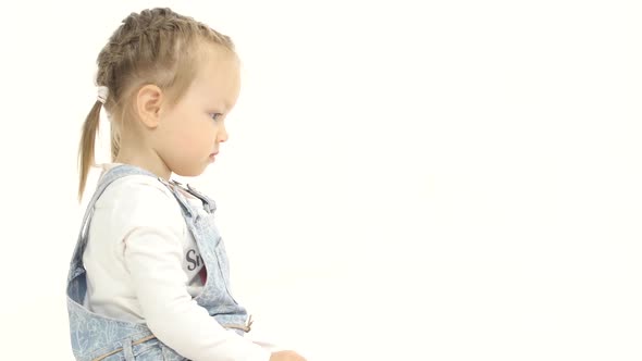 Little Girl Is Sitting on Her Lap and Looking at the Laptop. White Background