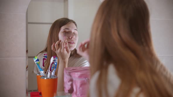 A Young Woman Applying Shadows on the Eyes