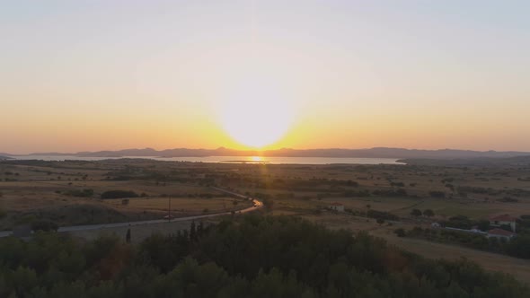 Aerial Drone View of Rural Landscape with Cars Driving Along Coastal Road with Scenic Sunrise