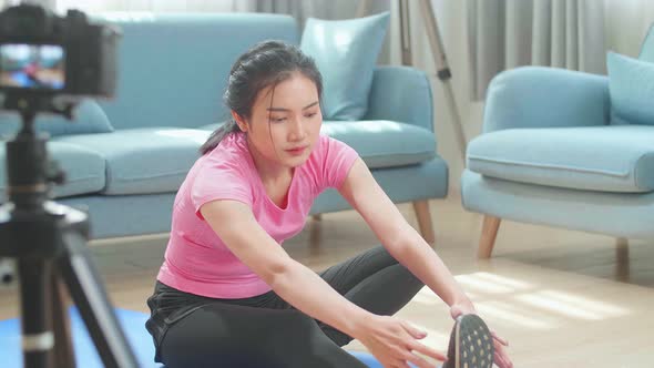 Asian Woman Blogger Exercising At Home And Shoots Video On Camera. Stretching Workout