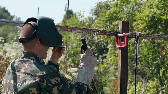 Slow Motion Man Welds and Checks Fence Part Fixed with Clamp