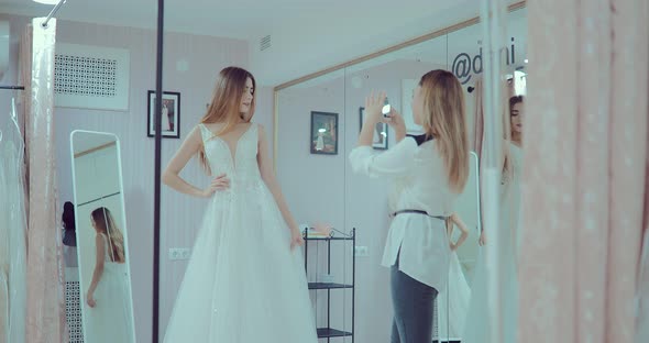 Beautiful Girl Wore an Elegant Wedding Dress and Does a Fitting in Front of a Mirror