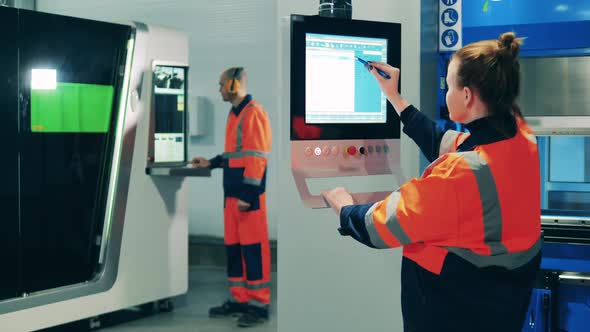 Female Factory Worker Using Stylus To Operate a Machine