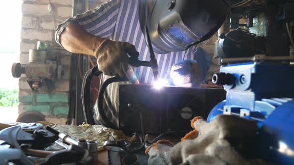 Repairer Welding Some Detail of Auto. Mechanic Working in Garage or Workshop with Welding Machine